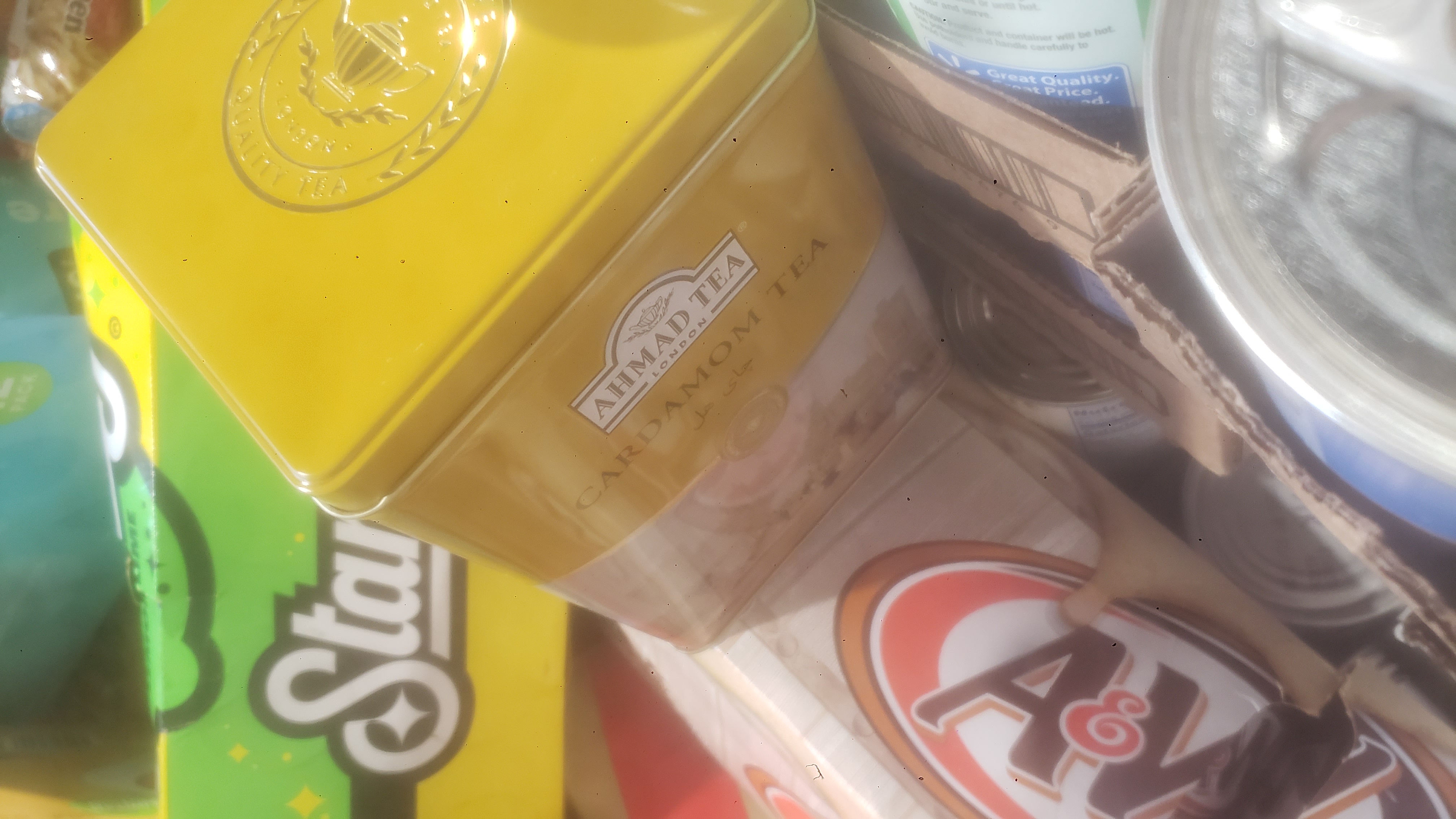 Tin of cardamom tea on the top of boxes of soda.